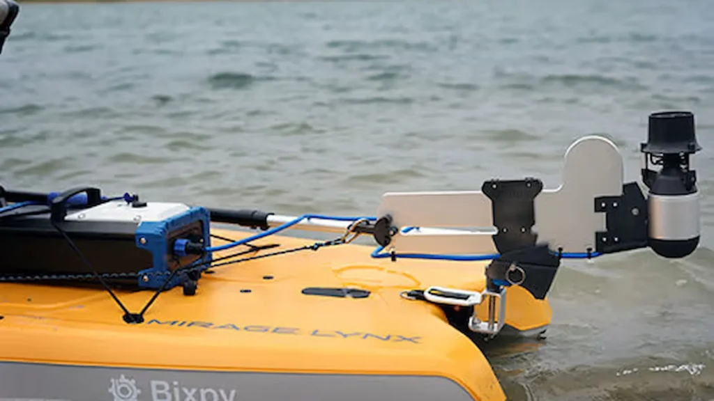 Bixpy K-1 motor mounted on the stern of a yellow kayak in shallow water