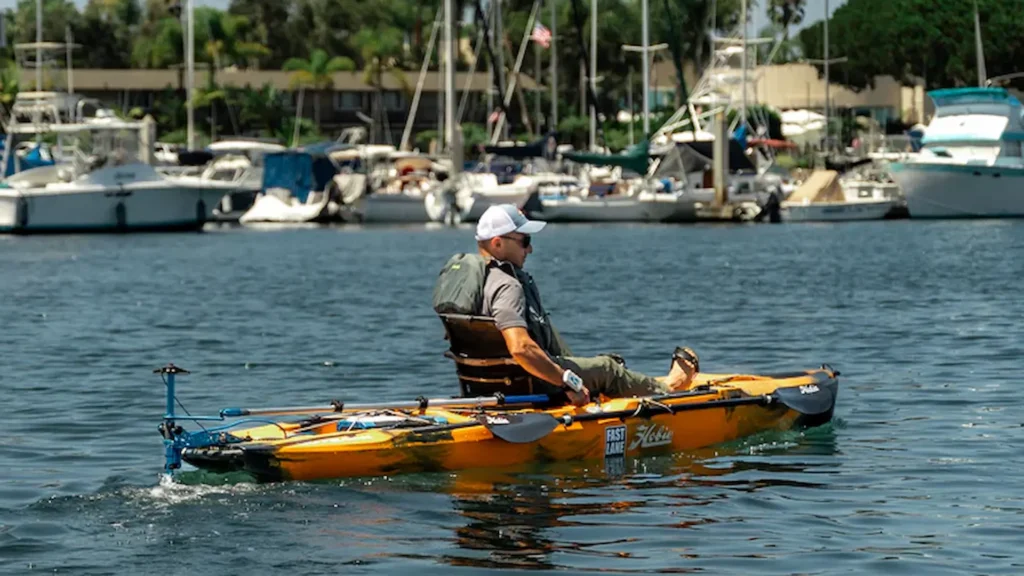 Man seated on a yellow kayak powered by a Bixpy motor in a marina harbor