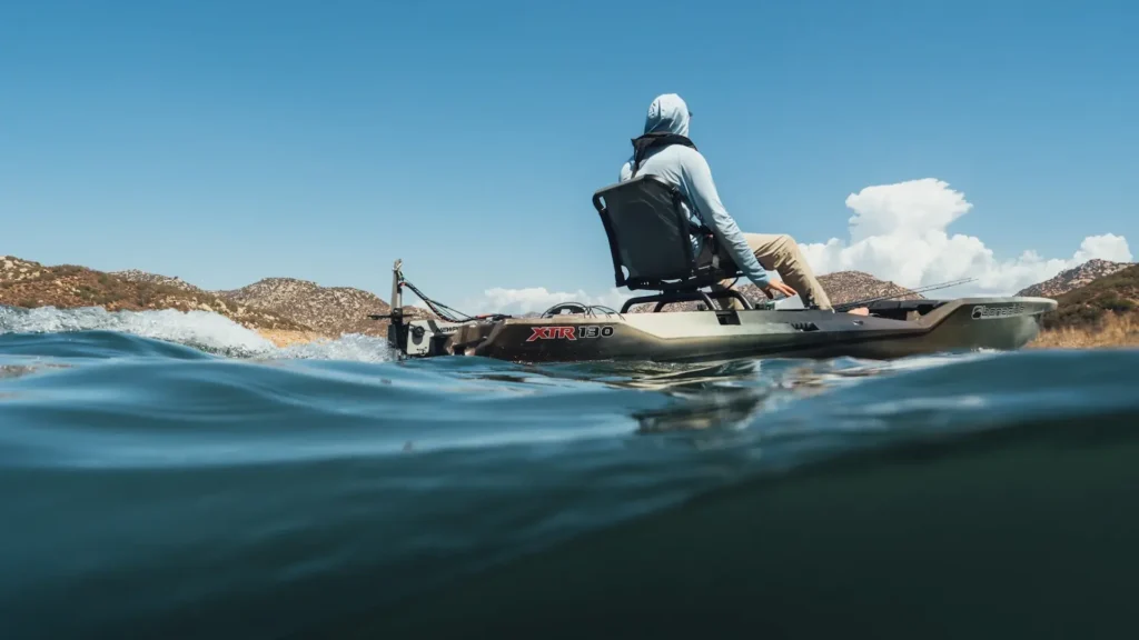 Angler seated on a fishing kayak powered by a Newport Vessels electric motor on a lake.
