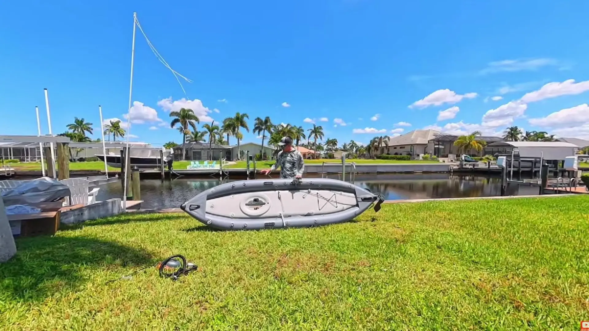 Saturn FPK365 inflatable pedal kayak being assembled on the grass beside a waterfront dock.
