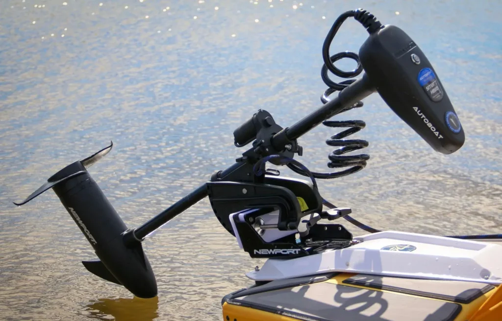 A TBNation AutoBoat GPS Smart Head retrofitted onto a Newport Vessels transom mount trolling motor, deployed in the water on a sunny day.
