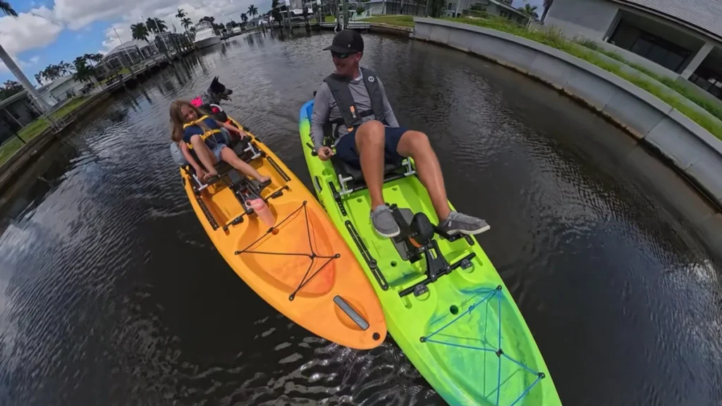 Two Old Town Malibu PDL pedal kayaks with family and dog on the water