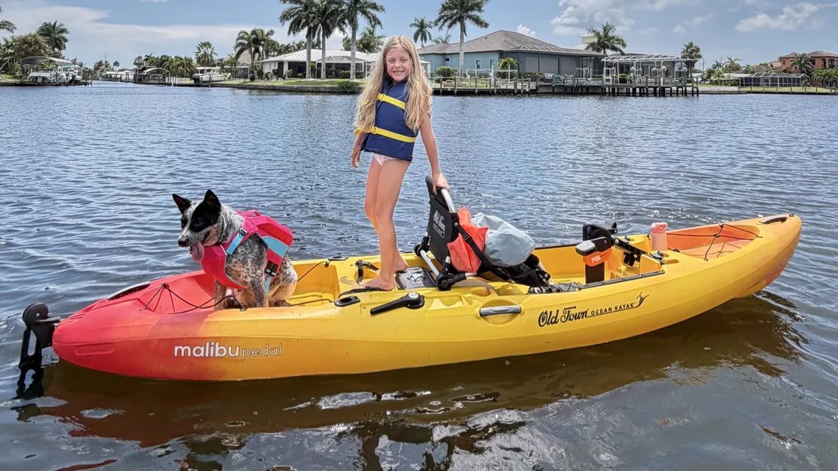 Girl standing with dog on a stable Old Town Malibu PDL kayak